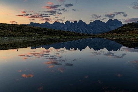 Salfainsee with reflection of the Kalkkoegel and mountaineers on mountain meadow at sunrise