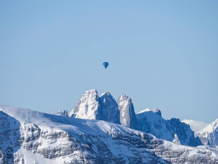 Hot air balloons flying over snow-covered Alpine peaks