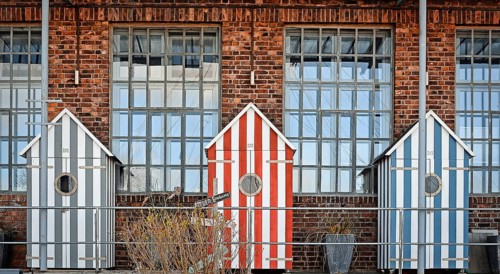 Three bathhouses in front of old industrial building