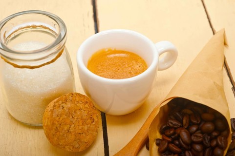 Espresso coffee and beans on a paper cone cornucopia over white background