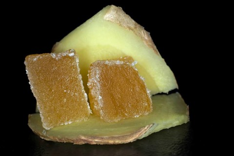 Two cubed candied ginger lies on a slice of fresh ginger