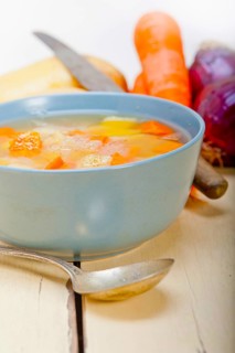 Traditional Italian minestrone soup on a rustic table with ingredients