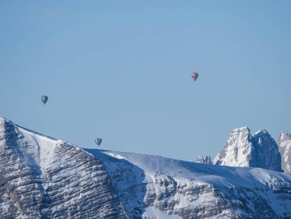 Hot air balloons flying over snow-covered Alpine peaks