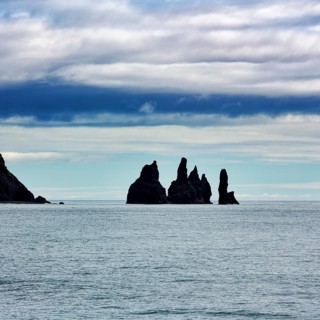 Cloudy sky above rock needles Reynisdrangar in summer
