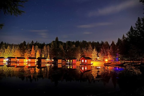 Small wooden holiday cabins at night on the shore of a lake