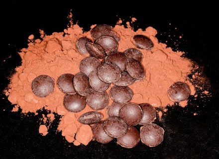 Dark couverture chocolate drops lying on cocoa powder