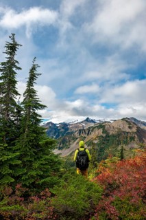 Hiker in front of Mt. Baker in clouds with snow and glacier
