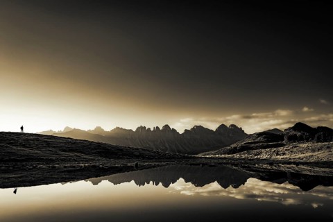 Salfainsee with reflection of the Kalkkoegel and mountaineers on mountain meadow at sunrise