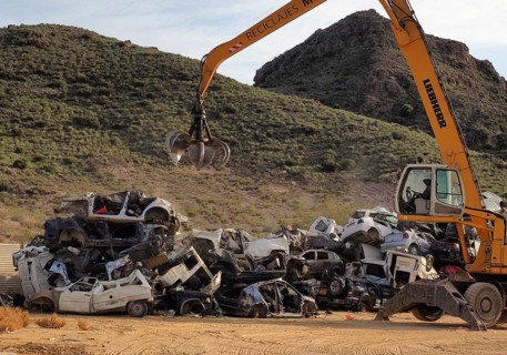 Crane piles scrap car on top of other cars