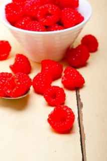 Bunch of fresh raspberry on a bowl and white wood rustic table