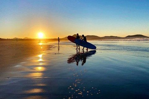Surfers on Caleta de Famara beach at sunset
