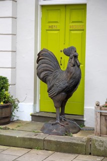 Large metal cockerel sculpture chained outside Hen House