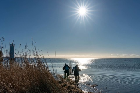 Two anglers in the backlight at the lighthouse of Maltzien on the island of Ruegen
