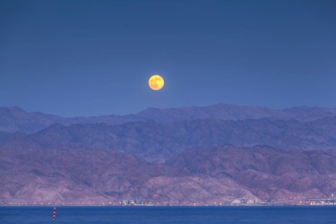 Afull moon over the desert of Akaba in Jordan as seen from the shores of Eilat