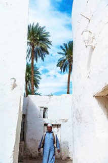 An elderly Berber man walking through the whitewashed buildings of Ghadmes