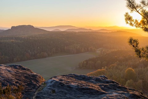 Rocks and vantage point on Pfaffenstein with view of Table Mountain Gohrisch at sunrise