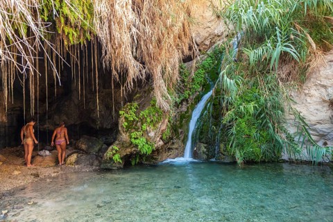 Two young women in one of the caves with a stream dating back to biblical times in the Negev desert in the Nature Reserve of Ein Gedi