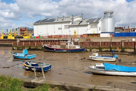 Boats at low tide in muddy creek by Trinity House