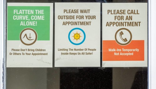 Covid-19 notices about precautions to be taken on glass window of hairdresser shop