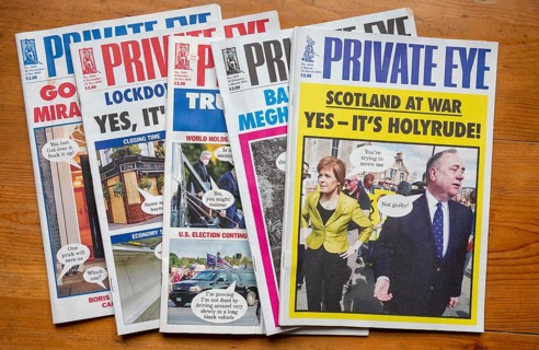 Front covers of editions of Private Eye satirical magazines viewed from above