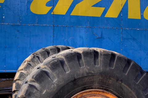 Tyres from tractor in front of blue metal from scrap car
