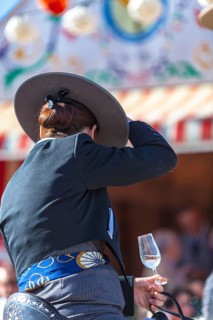 Detail of woman in traditional attire with sherry glass in hand during the Feria de Abril in Seville