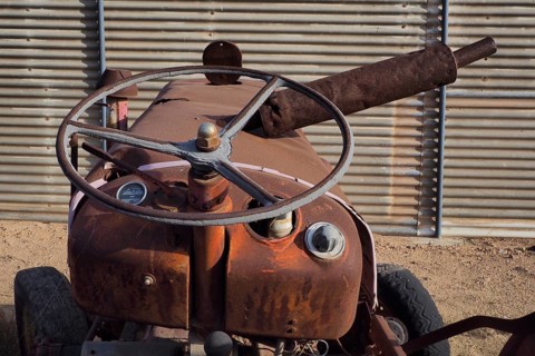 Rusty bonnet of tractor with steering wheel