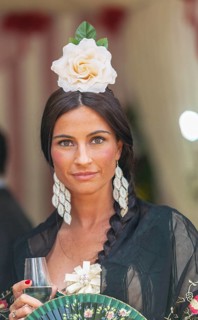 Portrait of a beautiful young woman in traditional attire and sherry glass in hand during the week-long Feria de Abril in Seville