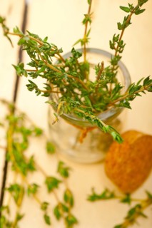 Fresh thyme on a glass jar over a white wood rustic table