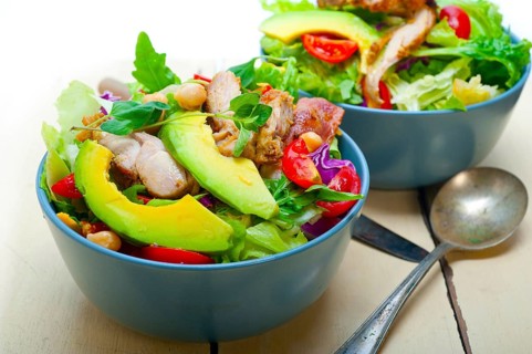 Fresh and healthy Chicken Avocado salad over rustic wood table