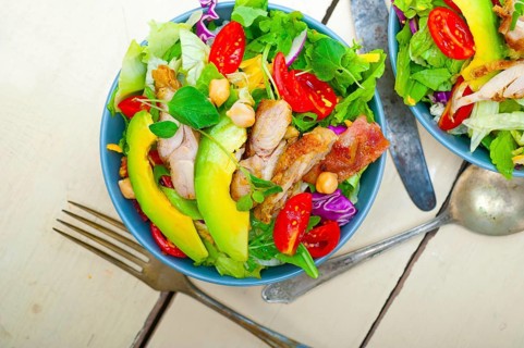 Fresh and healthy Chicken Avocado salad over rustic wood table