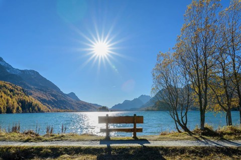 Lake Silsersee with bench and sun in autumn