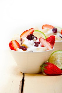 Fruit and yogurt salad healthy breakfast over white wood table