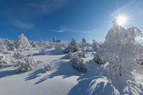 Snow covered winter landscape with sun Fichtelberghaus and weather station