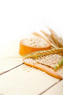 Organic barley grains over rustic wood table macro closeup