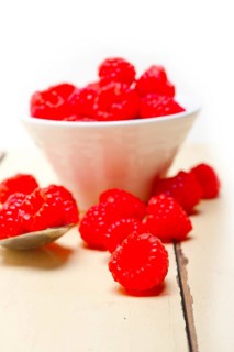 Bunch of fresh raspberry on a bowl and white wood rustic table