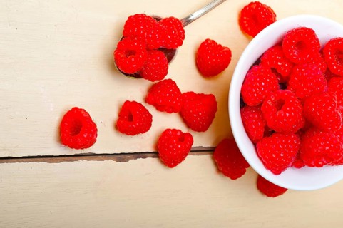 Bunch of fresh raspberry on a bowl and white wood rustic table