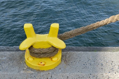 Rope and yellow mooring bollard in seaport