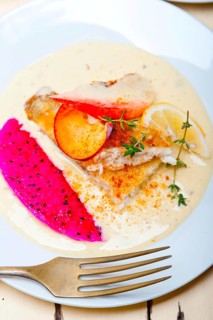Sea bream orata fillet butter pan fried with fresh peach prune and dragonfruit slices thyme on top