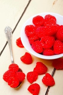 Bunch of fresh raspberry on a bowl and white wood rustic table
