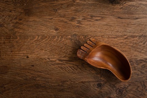 Wooden bowl in the shape of a foot on a wooden table