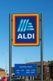 Aldi shop sign with opening hours against blue sky