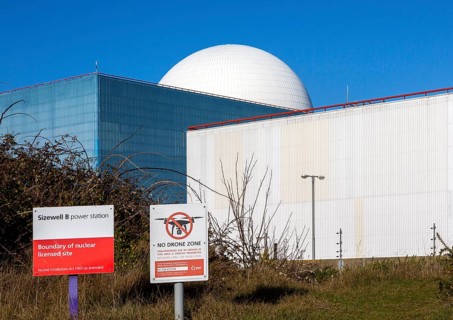 Signs boundary and no drone zone with white dome of Sizewell B power station