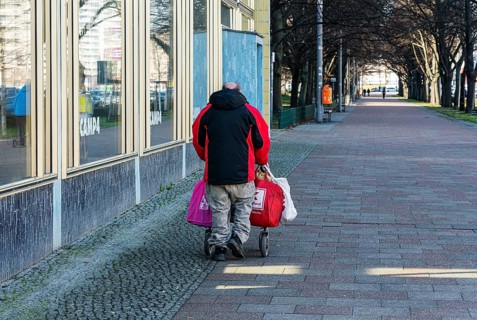 Senior citizen with walking frame and bags full of returnable bottles
