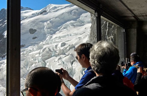 Tourists look through a glass window at the Eigerwand station of the Jungfrau Railway at the ice quarries of the Eiger Glacier