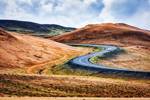 Winding asphalt road through hilly landscape