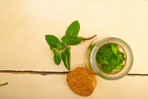 Fresh mint leaves on a glass jarover a rustic white wood table