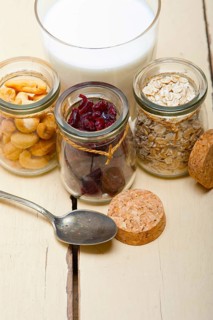 Healthy breakfast ingredients milk oat cashew nuts dried cramberry craisinns