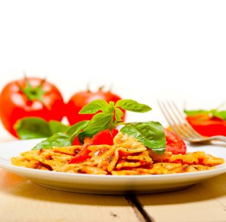 Italian pasta farfalle butterfly bow-tie with tomato basil sauce over white rustic wood table