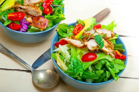 Fresh and healthy Chicken Avocado salad over rustic wood table